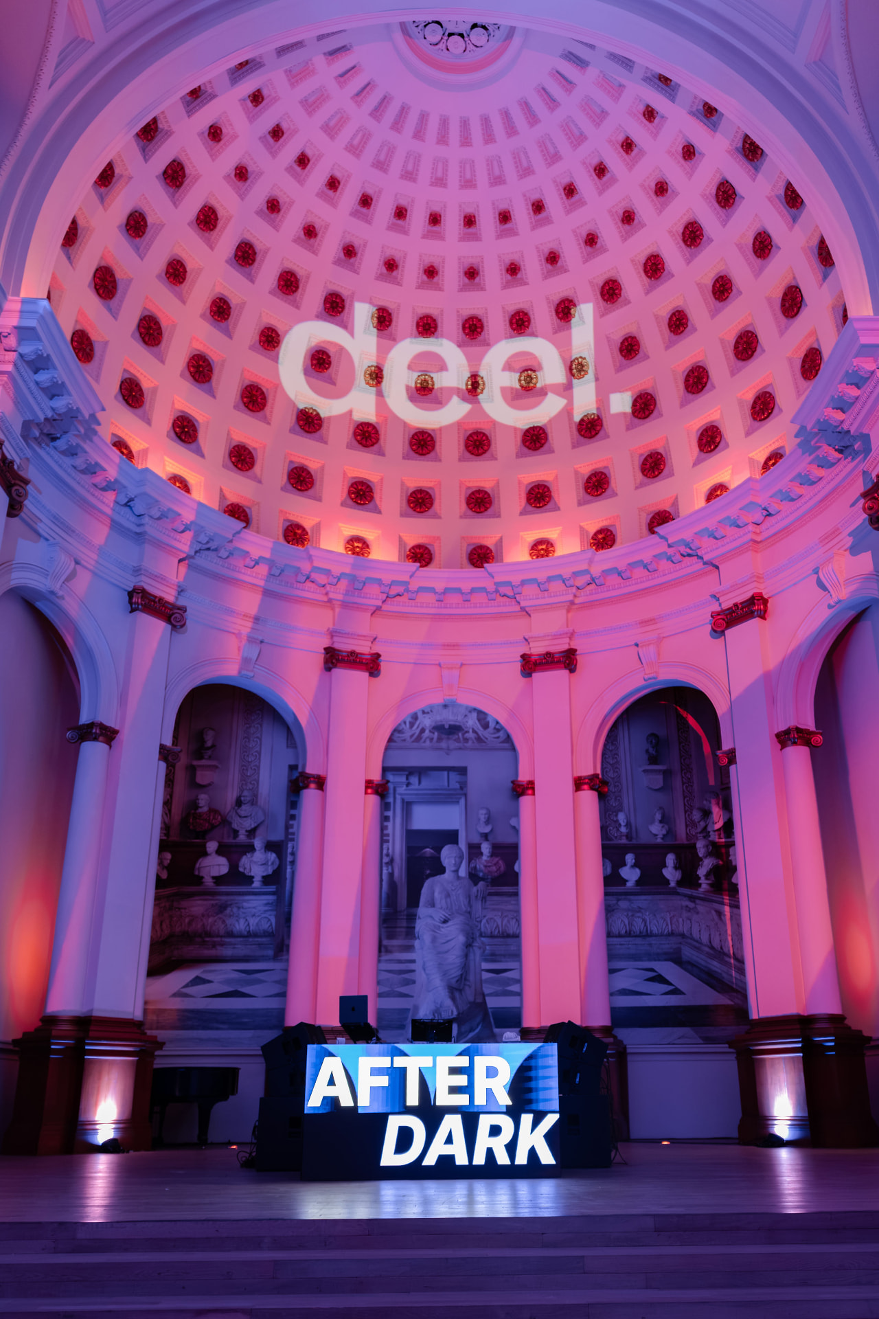 The deel. logo projected across the dome of a former church above the illuminated AFTER DARK DJ booth, lit in violet