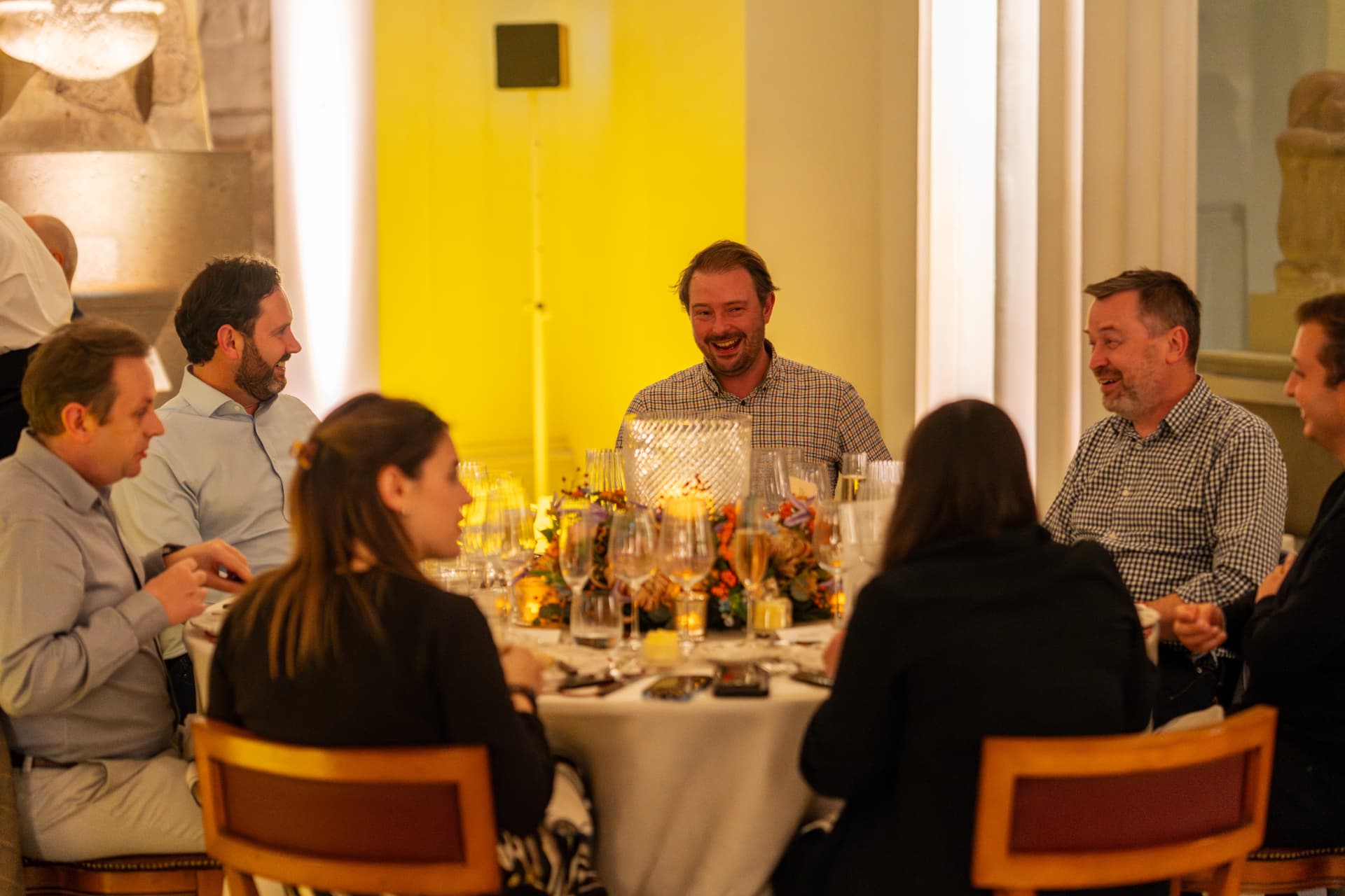 Guests in conversation around a candlelit round table in the museum gallery
