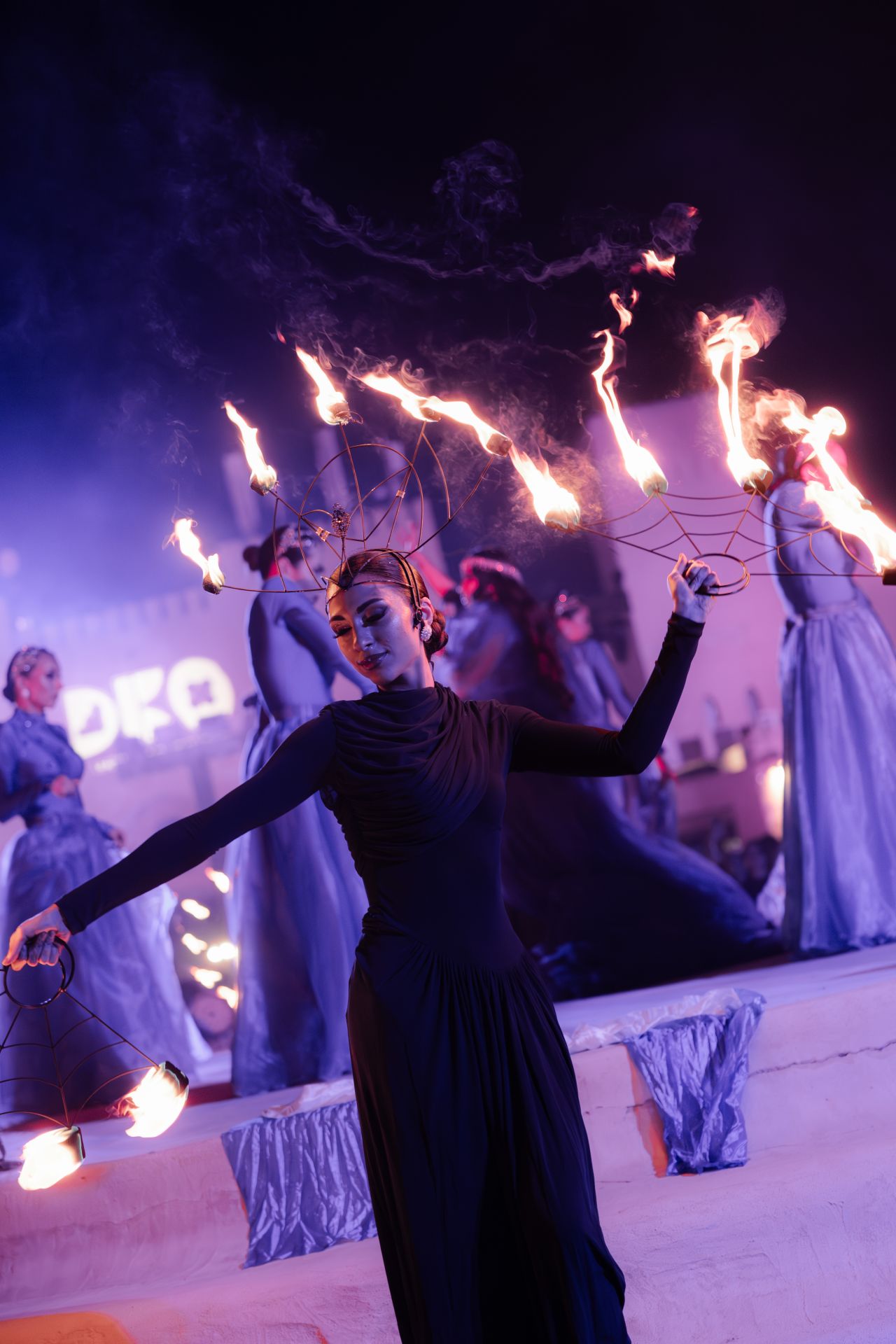 A fire performer in the desert with the illuminated fort set behind her